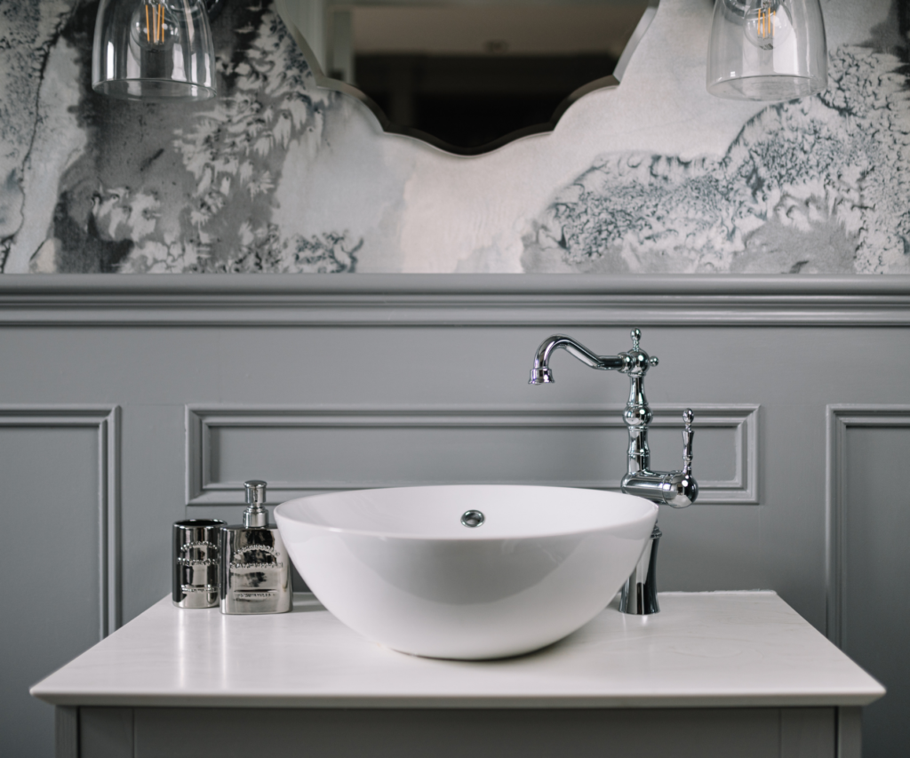 Modern bathroom sink with wood panel splashback and grey wallpaper