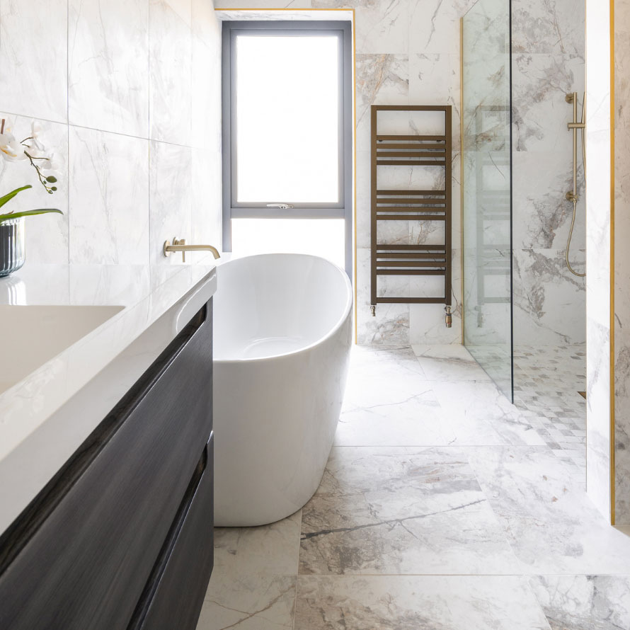 Portrush self build customer bathroom with marble effect tiles, freestanding bath and dark wood effect unit